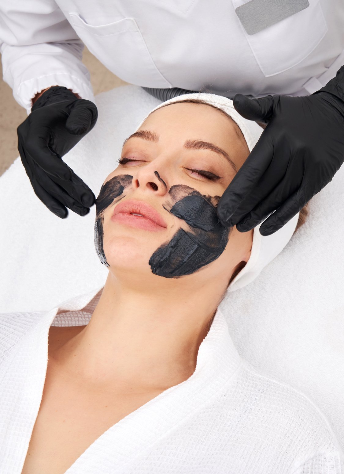 Cosmetologist Applying Black Mask on the Face of a Beautiful Woman for Carbon Peel